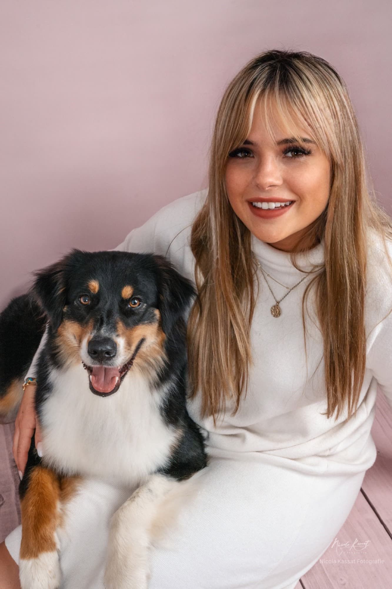 Fabienne Leibold lächelt und hält einen dreifarbigen Australian Shepherd im Arm